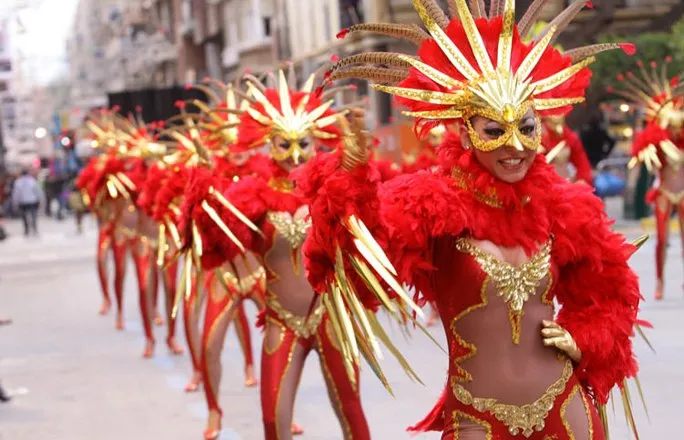 Bailarinas con trajes rojos de plumas y máscaras doradas en el desfile del Carnaval de Águilas