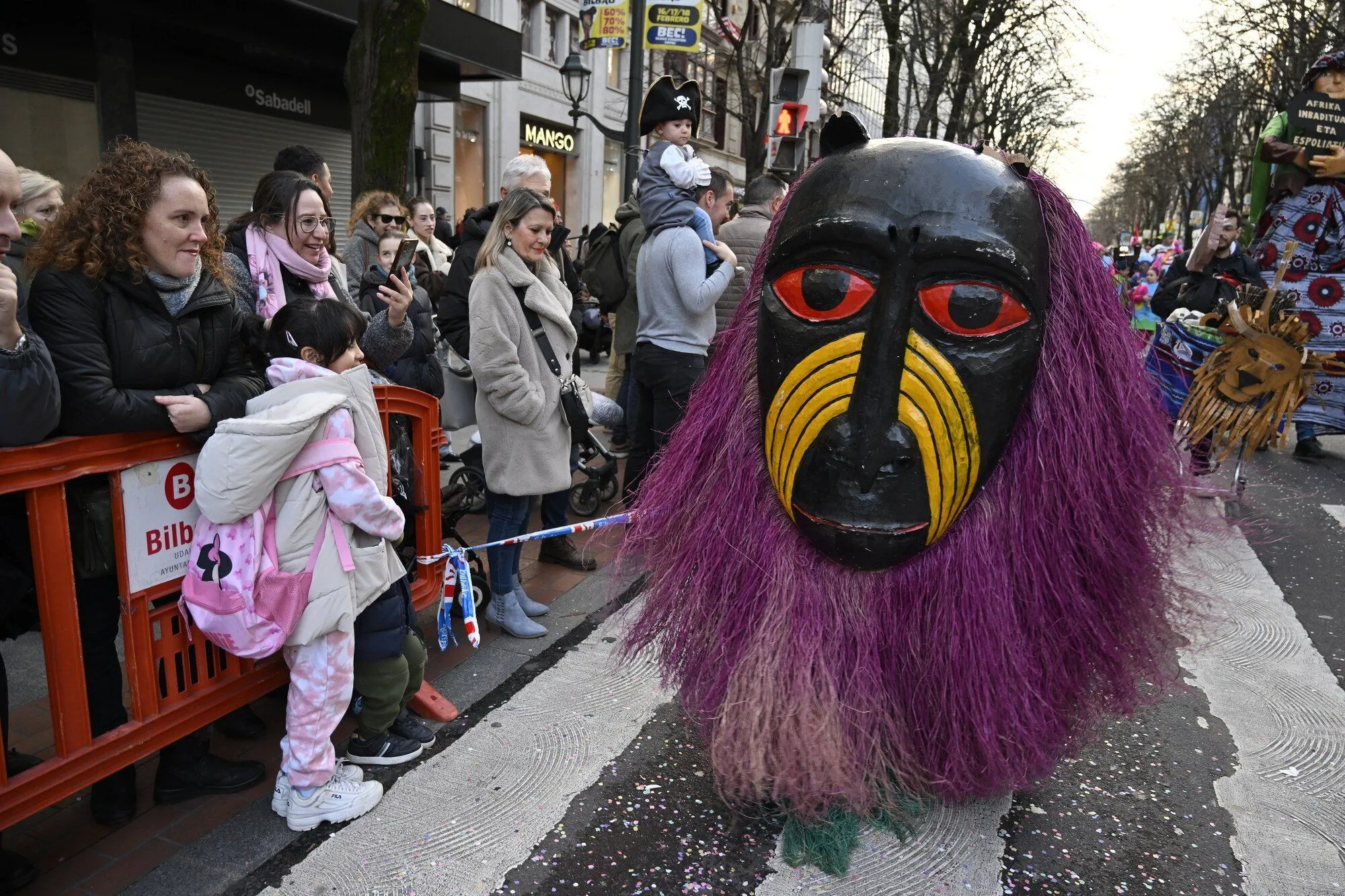 Máscara gigante africana con pelo morado entre el público del Carnaval de Bilbao