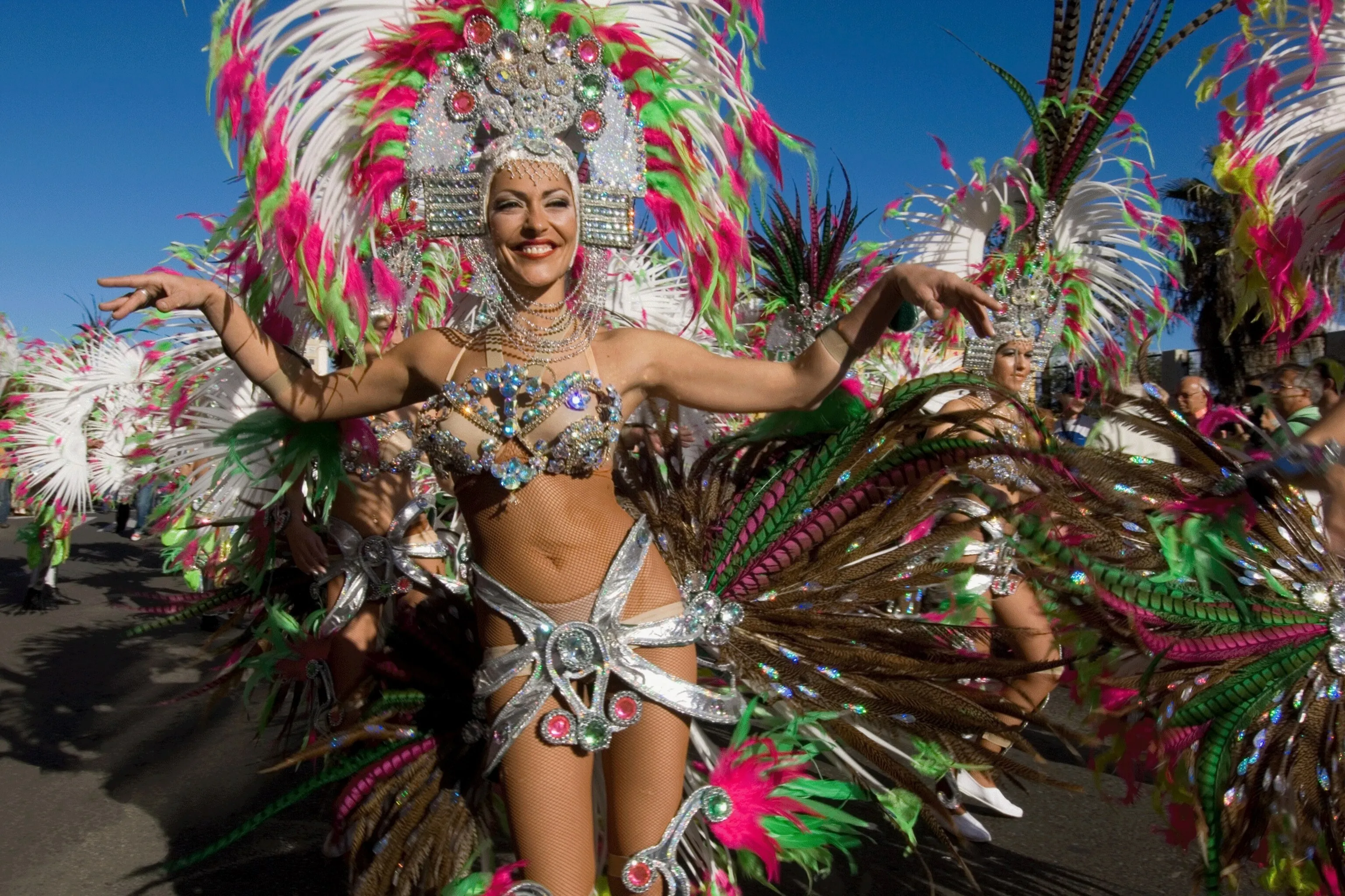 Bailarina con traje de plumas rosas, verdes y plateadas en la cabalgata del Carnaval de Las Palmas