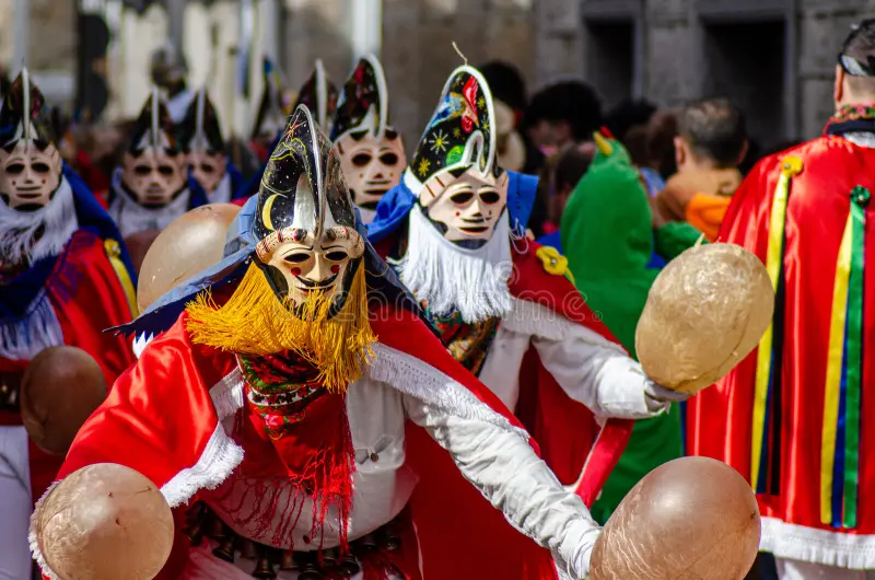 Pantalla tradicional con máscara tallada y traje de flecos en las calles de Ourense