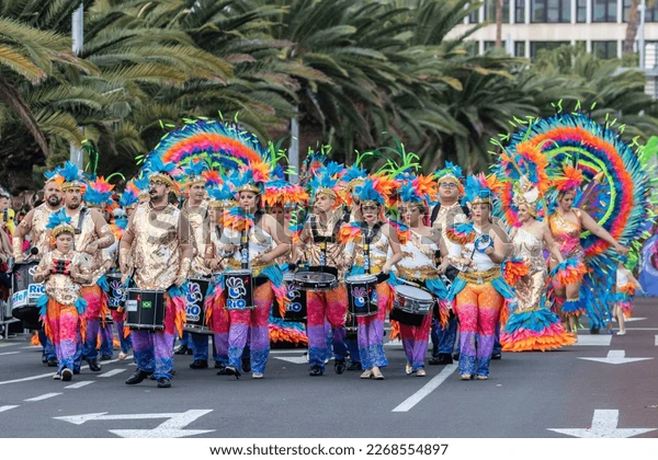 Batucada con trajes de plumas azules y naranjas en la avenida del Carnaval de Tenerife